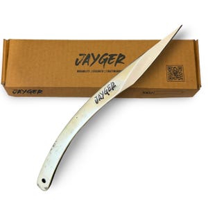 May include: A silver-colored throwing knife with a curved blade, resting in front of a brown cardboard box. The box is labeled "JAYGER" with the words "DURABILITY | STRENGTH | CRAFTMANSHIP" below. The knife also has the word "JAYGER" on it.