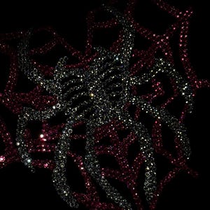 May include: A black fabric surface featuring a central spider design crafted from shimmering silver rhinestones, layered over a larger web pattern composed of deep red rhinestones. The design is set against a dark background with subtle text.