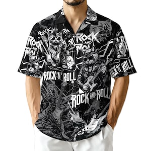 May include: Black and white short-sleeve button-down shirt with a repeating pattern of rock and roll cats playing instruments. The shirt features the words "Rock and Roll" in a bold font.