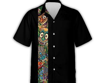 Peut inclure: Chemise noire à manches courtes avec un panneau vertical coloré représentant des visages de tiki de dessins animés et un feuillage tropical. La chemise a un col classique et des boutons blancs, offrant un contraste vif avec le tissu noir uni.