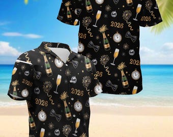Peut inclure: Chemise noire à manches courtes avec un motif festif de bouteilles de champagne, d'horloges, de nœuds papillon et l'année "2026" en or. L'arrière-plan est une plage.