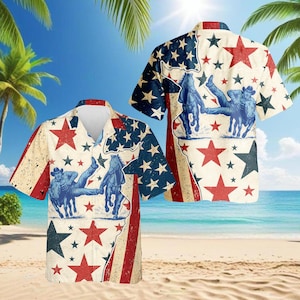 Op de afbeelding: Korte mouwen overhemd met een patriottisch ontwerp. Het overhemd heeft een versleten Amerikaans vlagmotief met rode, witte en blauwe sterren en strepen, en een cowboy die een paard berijdt. Het overhemd wordt op een strand getoond.