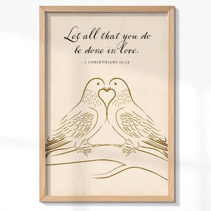 May include: Framed art print featuring two doves forming a heart with their beaks. The artwork is in a minimalist style with gold-colored line art on a cream background. The text "Let all that you do be done in love" is at the top, with "1 CORINTHIANS 16:14" below.