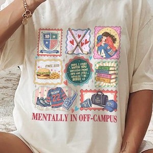 Puede incluir: Camiseta de color crema con un diseño gráfico colorido que presenta varias ilustraciones dentro de marcos tipo sello postal. La camiseta incluye el texto "MENTALLY IN OFF-CAMPUS" y otras frases.
