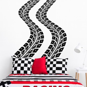 May include: A racing-themed bedroom set featuring a black, white, and red color scheme. The bedding includes a duvet cover with the word "RACING" and checkered flag pillows. Black tire track decals adorn the white wall.