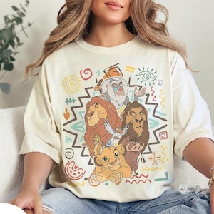 Puede incluir: Camiseta color marfil con un gr&aacute;fico colorido de personajes de El Rey Le&oacute;n. El dise&ntilde;o incluye a Simba, Mufasa, Scar, Tim&oacute;n, Pumba y Rafiki, rodeados de patrones tribales. La camiseta tiene un corte holgado.