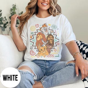 Puede incluir: Camiseta blanca con un gr&aacute;fico colorido de personajes de El Rey Le&oacute;n. El dise&ntilde;o incluye a Simba, Mufasa, Tim&oacute;n, Pumba y Zaz&uacute;, con patrones tribales decorativos en el fondo. La camiseta es de corte holgado.