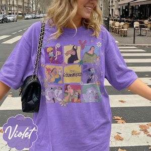 May include: A violet short-sleeved t-shirt featuring a grid of characters from the movie The Emperor's New Groove. The graphic includes Kuzco, Pacha, Yzma, and Kronk in various panels, with the text Disney The Emperor's New Groove in the center.