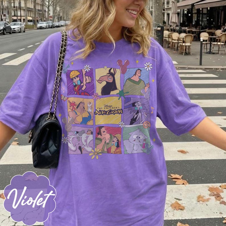 May include: A violet short-sleeved t-shirt featuring a grid of characters from the movie The Emperor's New Groove. The graphic includes Kuzco, Pacha, Yzma, and Kronk in various panels, with the text Disney The Emperor's New Groove in the center.