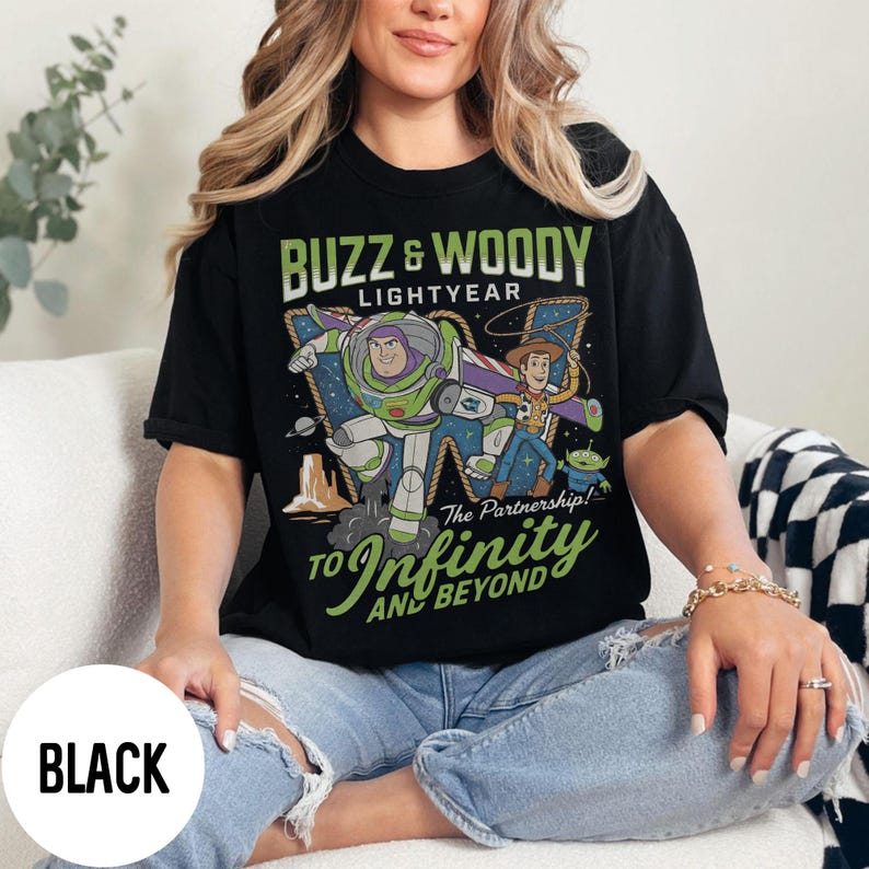 May include: Black crew neck t-shirt featuring Buzz Lightyear and Woody from Toy Story. The graphic includes the text "Buzz & Woody Lightyear" and "To Infinity and Beyond".