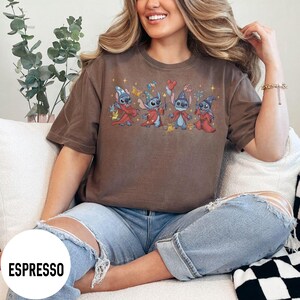 May include: Espresso-colored t-shirt featuring a graphic of four cartoon characters in wizard attire. The characters are blue with various accessories. The shirt is a solid color with the word "ESPRESSO" in a white circle at the bottom.