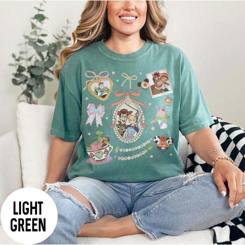 May include: Light green t-shirt featuring various cartoon character graphics. The shirt includes images of Buzz Lightyear, Woody, and other characters. The words "LIGHT GREEN" are printed on a white circle at the bottom left of the image.