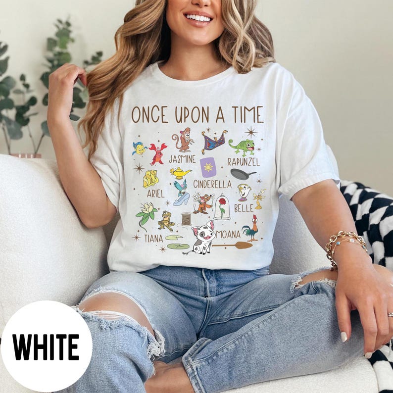 May include: White t-shirt with the text "ONCE UPON A TIME" and cartoon illustrations of characters including Jasmine, Rapunzel, Ariel, Cinderella, Belle, and Moana. A fun, colourful design.