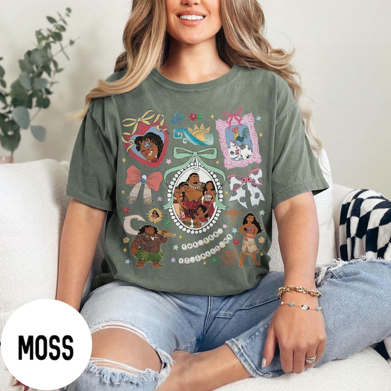 Pu&ograve; includere: T-shirt verde muschio con un design grafico colorato con personaggi ed elementi di un popolare film d'animazione. Il design include ritratti incorniciati, fiocchi e altri elementi decorativi. La parola "MOSS" &egrave; stampata su un cerchio bianco.