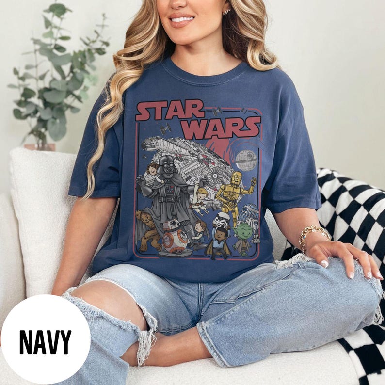 May include: Navy blue Star Wars graphic t-shirt featuring Darth Vader, the Millennium Falcon, and other characters. The text "STAR WARS" is displayed in red. The shirt is a comfortable, casual style.