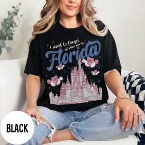 May include: Black t-shirt with the text "I need to forget so take me to Florida" in blue script. The shirt features a pink and white castle graphic with balloons. The word "BLACK" is in a white circle at the bottom.