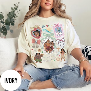 Pu&ograve; includere: T-shirt color avorio con un design grafico colorato con personaggi ed elementi di un popolare film d'animazione. Il design include ritratti incorniciati, fiocchi e la scritta "THE SEA CALLS ME".