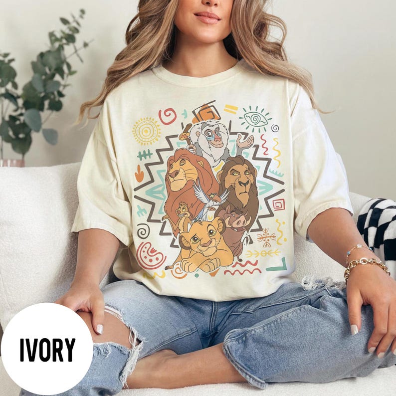 Puede incluir: Camiseta color marfil con un gr&aacute;fico colorido de personajes de El Rey Le&oacute;n. El dise&ntilde;o incluye a Simba, Mufasa, Scar, Tim&oacute;n, Pumba y Rafiki, rodeados de patrones tribales. La camiseta tiene un corte holgado.