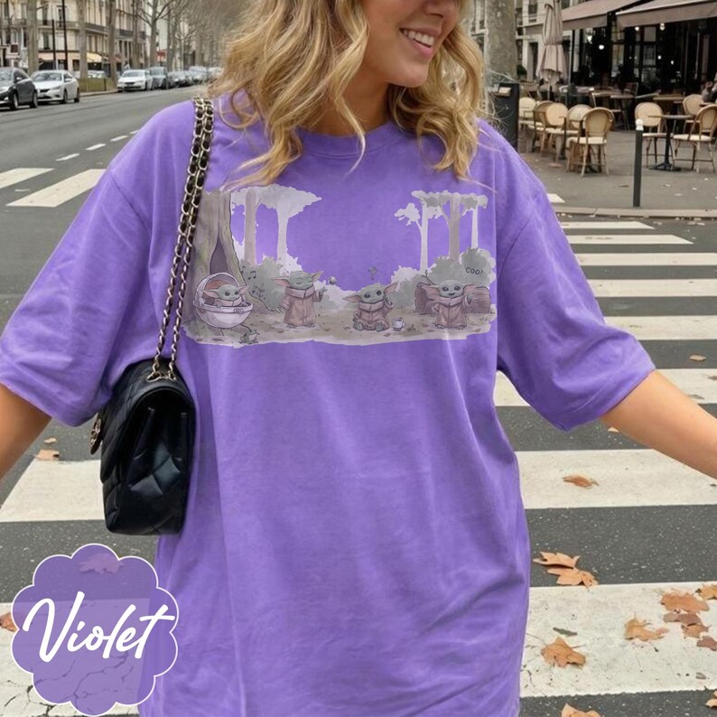 Puede incluir: Camiseta violeta con un gr&aacute;fico de un personaje de una popular serie de ciencia ficci&oacute;n. El dise&ntilde;o muestra al personaje en un entorno forestal. La camiseta tiene mangas cortas y un corte holgado.