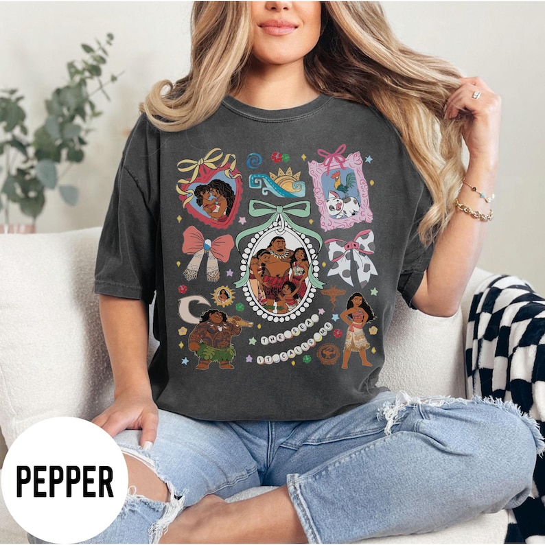Pu&ograve; includere: T-shirt grigio scuro con un design grafico colorato con personaggi ed elementi di un popolare film d'animazione. Il design include ritratti, fiocchi e una cornice ovale centrale con un ritratto di famiglia. La parola "PEPPER" &egrave; in basso.