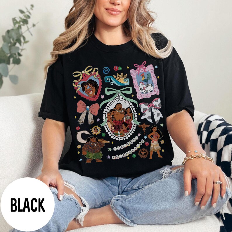 Pu&ograve; includere: T-shirt nera con un design grafico colorato con personaggi ed elementi decorativi. Il design include un ovale centrale con un ritratto di famiglia e varie immagini incorniciate e fiocchi. La parola "BLACK" &egrave; stampata su un cerchio bianco.