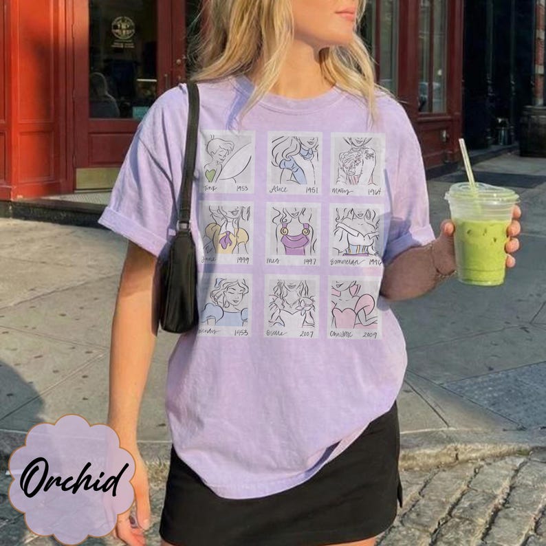 May include: A light purple t-shirt featuring a grid of cartoon illustrations of animated characters. The shirt has short sleeves and a crew neck. The word "Orchid" is printed on a light purple cloud-shaped design.