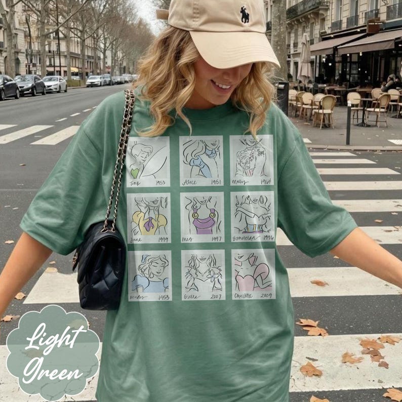 May include: Light green t-shirt with a grid of cartoon sketches and the text "Light Green". The sketches are of various characters. The shirt is a light green color.