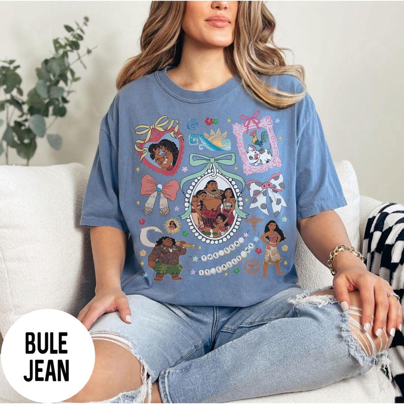 Pu&ograve; includere: Una maglietta blu con un design grafico colorato con personaggi ed elementi di un popolare film d'animazione. Il design include ritratti incorniciati, fiocchi e altri elementi decorativi. Il testo "BULE JEAN" &egrave; visibile in basso a sinistra.