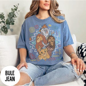 Puede incluir: Una camiseta azul claro con un gr&aacute;fico colorido de personajes de El Rey Le&oacute;n. El dise&ntilde;o incluye a Simba, Mufasa, Tim&oacute;n, Pumba y Rafiki, con patrones de inspiraci&oacute;n tribal. La camiseta tiene mangas cortas y un corte holgado.