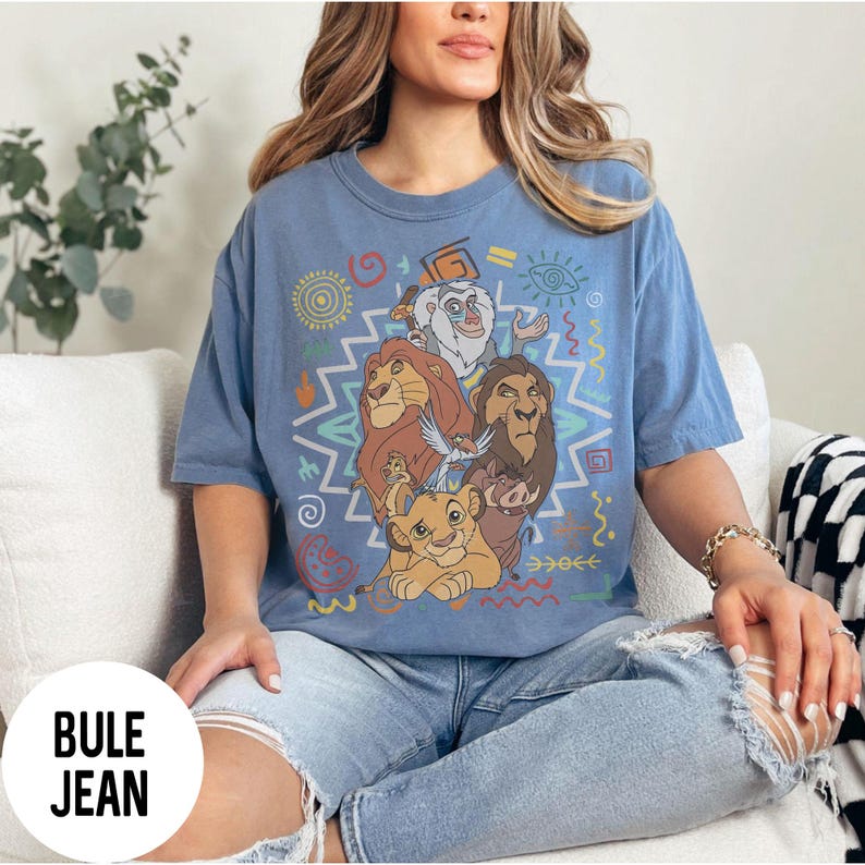 Puede incluir: Una camiseta azul claro con un gr&aacute;fico colorido de personajes de El Rey Le&oacute;n. El dise&ntilde;o incluye a Simba, Mufasa, Tim&oacute;n, Pumba y Rafiki, con patrones de inspiraci&oacute;n tribal. La camiseta tiene mangas cortas y un corte holgado.