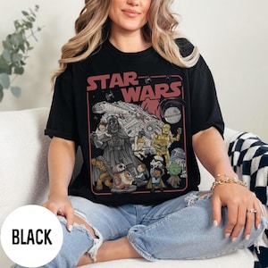 May include: Black t-shirt featuring a Star Wars graphic. The design includes Darth Vader, the Millennium Falcon, and other characters. The text "STAR WARS" is displayed in red. The shirt is a crew neck.