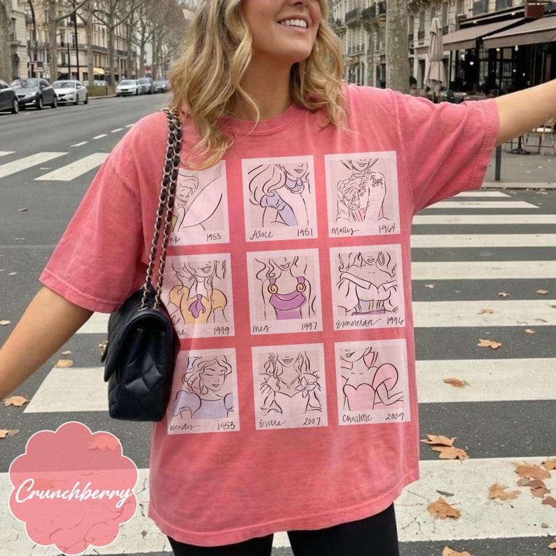 May include: A faded red t-shirt featuring nine cartoon illustrations of animated characters with dates. The text "Crunchberry" is at the bottom left. The shirt is worn by a person on a crosswalk.