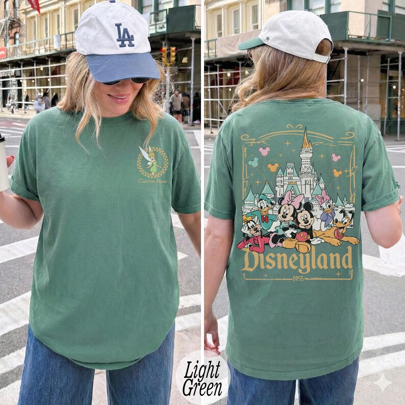 Pu&ograve; includere: T-shirt verde chiaro con grafica Disneyland sul retro, con Topolino, Minnie, Paperino, Paperina, Pippo e Pluto. La parte anteriore presenta una grafica di Trilli. Uno stile casual e confortevole.