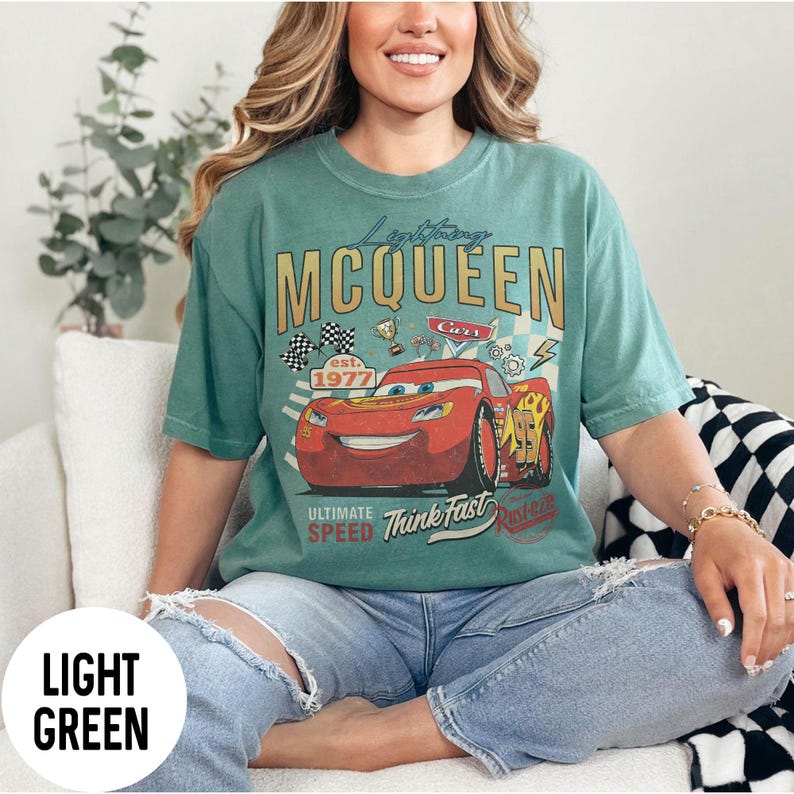 Op de afbeelding: Lichtgroen T-shirt met een afbeelding van Bliksem McQueen uit de film Cars. Het ontwerp bevat de tekst "Lightning McQueen" en "Ultimate Speed Think Fast". Het shirt heeft een vintage, verweerde uitstraling.