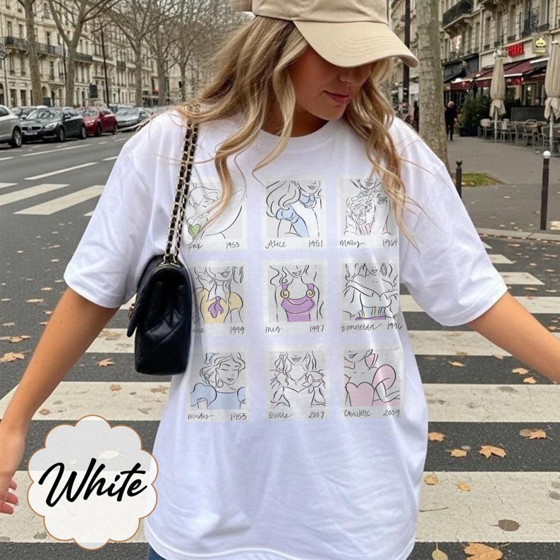 May include: White t-shirt featuring a grid of cartoon sketches of animated characters. The shirt has a crew neck and short sleeves. The word "White" is written in a decorative font at the bottom of the shirt.
