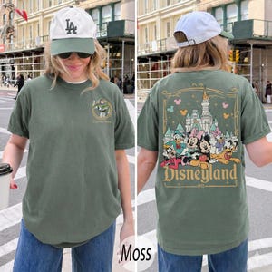 Pu&ograve; includere: T-shirt verde muschio con design Disneyland. La parte anteriore presenta una piccola grafica, mentre il retro mostra un design pi&ugrave; grande con personaggi Disney e il logo Disneyland. La maglietta &egrave; realizzata in materiale morbido e ha maniche corte.