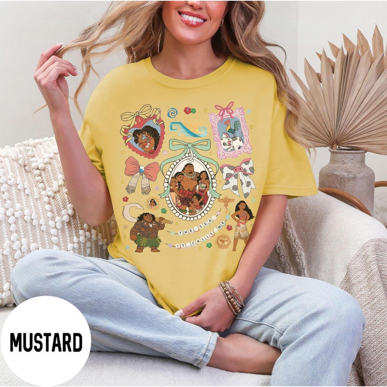 Pu&ograve; includere: T-shirt color senape con un design grafico colorato con personaggi di cartoni animati. Il design include ritratti incorniciati, fiocchi e la scritta "The Ocean Calls Me". La maglietta ha una vestibilit&agrave; ampia.