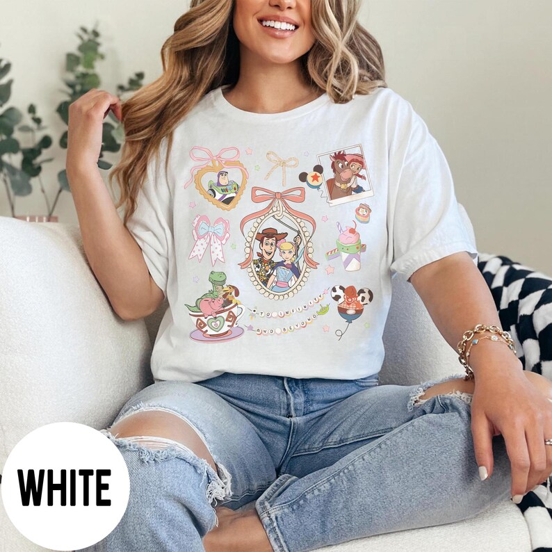 May include: White t-shirt featuring colorful cartoon character graphics. The design includes images of Buzz Lightyear, Woody, and other characters. The word "WHITE" is printed in a white circle at the bottom left.