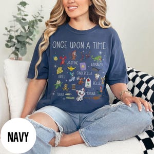 May include: Navy blue t-shirt with the text "ONCE UPON A TIME" and illustrations of Disney characters including Jasmine, Ariel, Cinderella, and Belle. The shirt has a crew neck and short sleeves, suitable for everyday wear.
