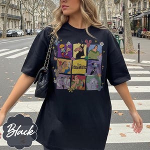 May include: A black short-sleeved t-shirt featuring a grid of colorful illustrations of characters from the movie The Emperor's New Groove, including the film's logo in the center, accented with small flower and musical note graphics.