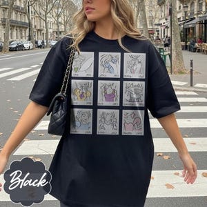 May include: Black t-shirt featuring a grid of nine cartoon illustrations of Disney princesses with their names and release years. The word "Black" is written in a white script on a black background.