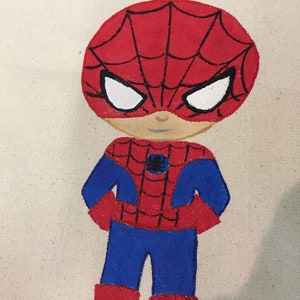 Puede incluir: Una bolsa de lona pintada a mano con una ilustraci&oacute;n de dibujos animados de Spiderman en rojo y azul, con el nombre "Nicholas" escrito sobre el personaje.