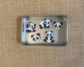 May include: A silver metal container with six black and white panda bear figurines inside.