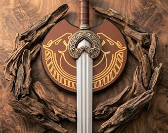 Puede incluir: Una espada plateada con empuñadura de cuero marrón y una guarda ornamentada de color bronce. La espada está montada sobre una placa circular marrón con dibujos de líneas doradas de dos cabezas de animales enfrentadas con cuernos.