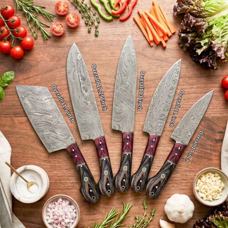Puede incluir: Cinco cuchillos de cocina con hojas de acero de Damasco y mangos de madera oscura. Los cuchillos miden 29,21, 31,12, 33,02, 27,94 y 25,4 cm en total. Las hojas presentan un patr&oacute;n ondulado y los mangos tienen una veta de madera oscura.
