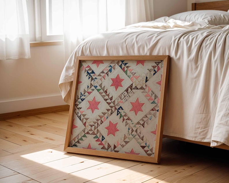 May include: A framed quilt with a wooden frame, featuring a repeating pattern of pink stars and geometric shapes in various colors. The quilt is leaning against a bed with white bedding, on a wooden floor.