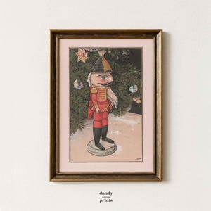 May include: Framed print of a vintage nutcracker soldier in a red uniform, black boots, and a tall hat. The background features a Christmas tree with ornaments. The print is in a gold frame, with the text "dandy vintage prints" at the bottom.