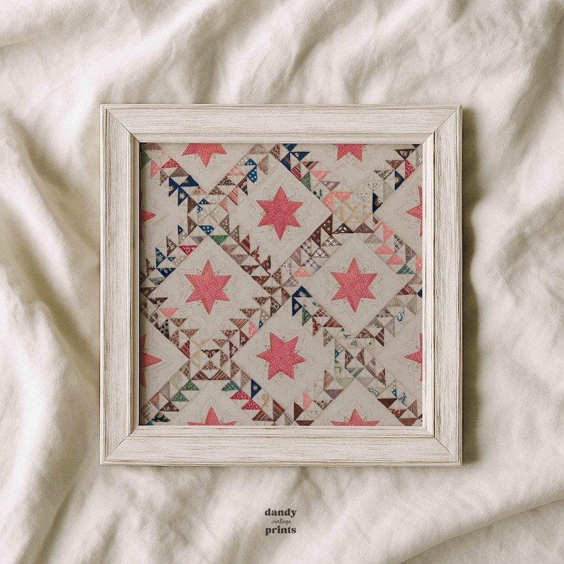 Printable vintage textile wall art featuring an antique quilt design of stars within squares in pinks, blues and beige. Displayed in a square wooden white frame.