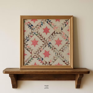 May include: Framed vintage quilt art featuring a repeating pattern of pink stars and geometric shapes in various colors. The artwork is displayed in a wooden frame and rests on a wooden shelf. The text "dandy prints" is visible.