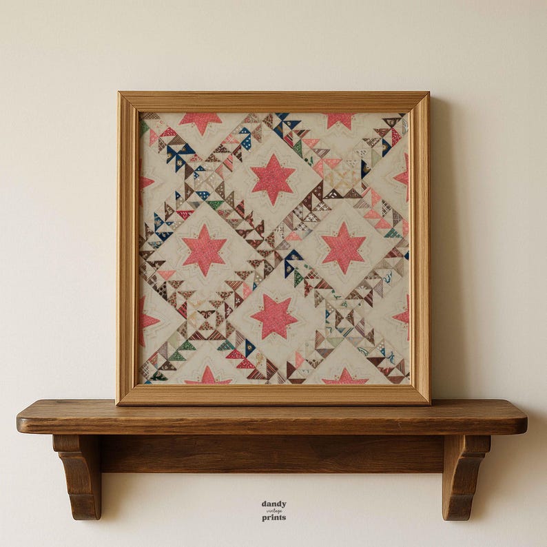 May include: Framed vintage quilt art featuring a repeating pattern of pink stars and geometric shapes in various colors. The artwork is displayed in a wooden frame and rests on a wooden shelf. The text "dandy prints" is visible.